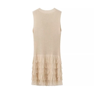 Gros plan d'une robe en maille beige avec pompons à franges multicouches et détails texturés
