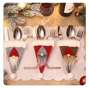 Three festive Christmas gnome cutlery holders in grey, red, and brown felt on a dinner table