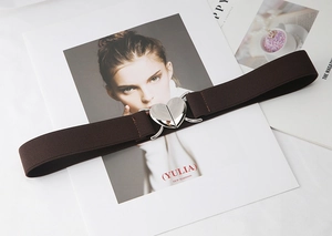 Détail d'une ceinture élastique marron avec boucle coeur argentée sur un magazine