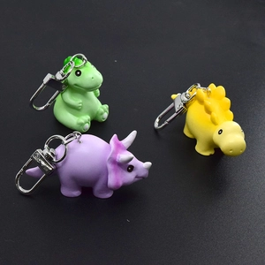 Set of three colorful cartoon dinosaur keychains in green yellow and purple resin