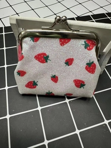 Sparkly white strawberry coin purse with silver metal clasp on a wooden stand