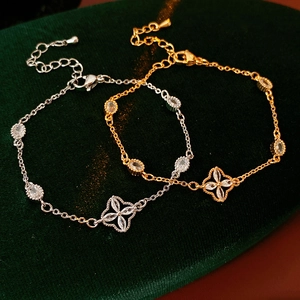 Macro detail of gold and silver flower bracelets with zircon inlay on green velvet