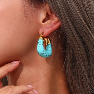Macro shot of gold-plated U-shaped earrings featuring turquoise marble resin textures