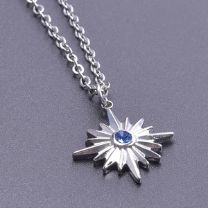 Macro detail of silver starburst pendant with a central blue zircon on a fine chain