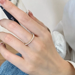 Close-up of gold-plated rings set with delicate micro pearls on a woman's finger