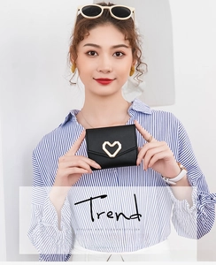 Close-up of stylish black mini wallet with a gold heart-shaped metal lock held by a hand