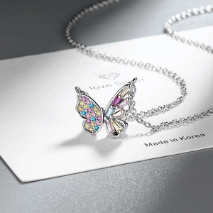 Détail macro du pendentif papillon argenté serti de zircons colorés sur une chaîne fine