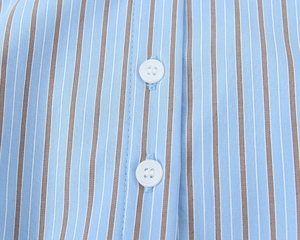 Détail macro du tissu en popeline à rayures bleu et marron avec boutons blancs ronds