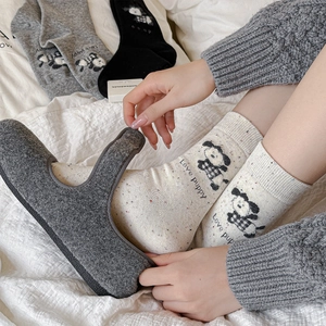 Knitted mid-calf cotton socks featuring puppy patterns and cozy felt slippers on a bed