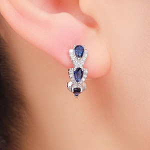 Close-up of elegant silver earrings featuring three blue zircon stones in a vertical row