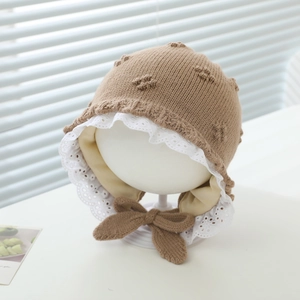 Detail of baby winter knit hat featuring delicate white lace trim and cozy earflaps