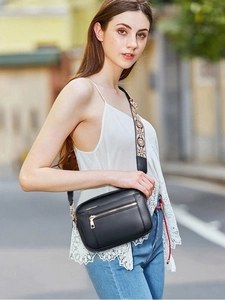 Close-up of black crossbody bag featuring ethnic pattern wide strap and golden hardware