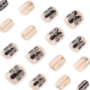 Uñas postizas cortas cuadradas con base rosa nude, flores negras y bordes plateados