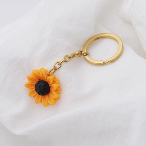 Detailed view of sunflower keychain petals and golden alloy ring on white linen fabric