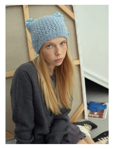 Detail of light blue cat ear knit beanie featuring delicate ribbon bow and soft yarn texture