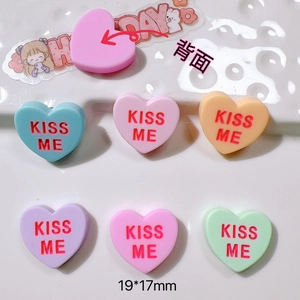 Macro detail of heart-shaped acrylic DIY charms in macaron colors with KISS ME text