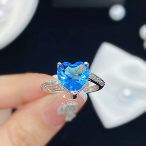 Anillo abierto de plata con gema azul en forma de corazón y detalles de circonita