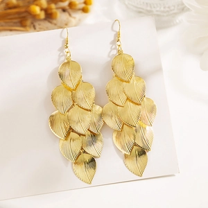 Gros plan de boucles d'oreilles feuilles dorées à plusieurs niveaux avec texture métal