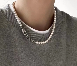 Nahaufnahme eines silbernen U-Verschlusses an einer weißen Perlenkette am Modell