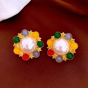 Macro detail of vintage gold earrings with large pearls and multi-colored bead accents