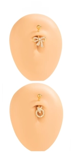 Detail of gold bow and circular navel rings with white zircons on silicone skin model