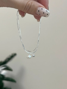 Macro detail of a double-layered S925 silver chain featuring a white pearl and silver bead