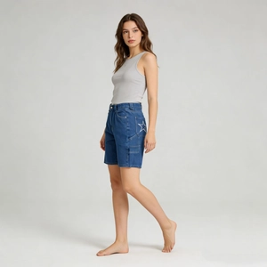 Dettaglio del ricamo a stella bianca sulla tasca laterale degli shorts in denim blu