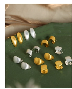 Detail of minimalist geometric gold and silver earrings with matte brushed metal finish