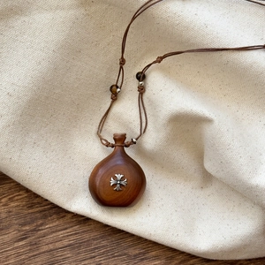 Macro shot of wooden pendant with silver cross ornament and detailed braided rope necklace