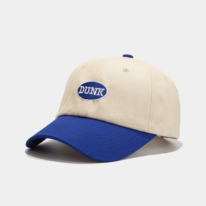 Detail of embroidered 'DUNK' logo on contrast beige and blue cotton baseball cap