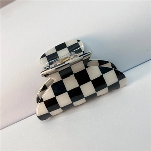 Macro detail of large black and white checkered hair claw clip with golden metal spring