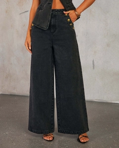 Détail du pantalon en jean gris à taille haute avec des boutons dorés sur le côté