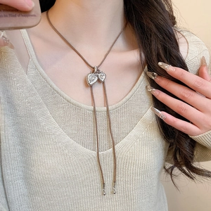 Detail of retro silver heart pendants on brown leather cord over knit sweater