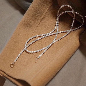 Detailed shot of s925 silver necklace with white freshwater pearls on camel wool fabric
