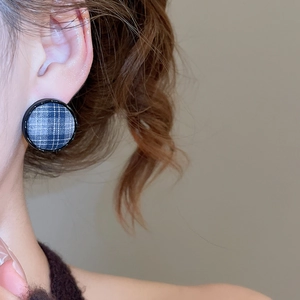 Close-up of retro blue checkered fabric stud earrings worn on a model ear