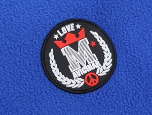 Detail of blue fleece fabric with embroidered M letter patch and decorative crown and star