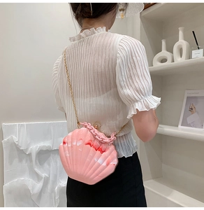 Detail of pink shell-shaped acrylic bag with marble texture and gold chain strap