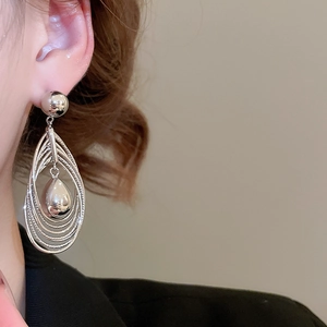 Close-up of layered silver teardrop earrings on model showcasing polished metal texture