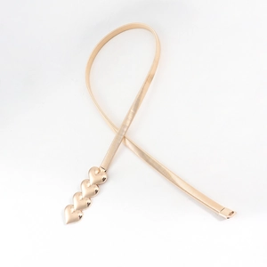 Detail of a golden metal elastic belt featuring four interlocking heart charms on a white background