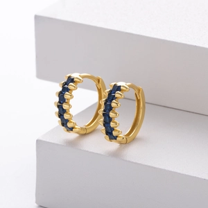 Detailed close-up of gold hoop earrings featuring square-cut deep blue sapphires