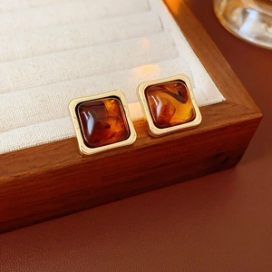 Detail of vintage square resin earrings in amber on a rustic wooden jewelry tray