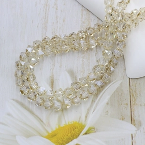 Macro shot of faceted champagne crystal glass beads with white daisy on wood