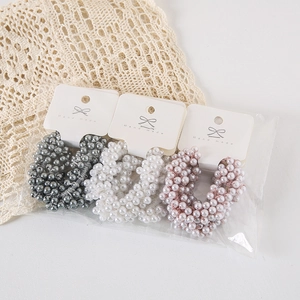 Three-piece set of woven pearl hair ties in grey, beige, and pink with handmade cards