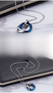 Macro shot of interlocking triple ring necklace featuring zircon inlay and sleek blue plating