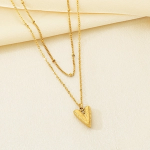Detailed close-up of a double-layered 18K gold-plated heart pendant on silk background
