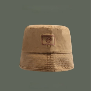 Detailed close-up of khaki canvas bucket hat fabric texture and D-letter embroidery patch