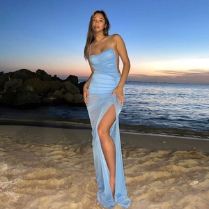 Detail of light blue mesh maxi dress with high slit and backless design on sunset beach