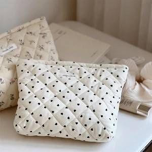 Cream quilted corduroy cosmetic bag featuring heart and floral patterns with zipper closure