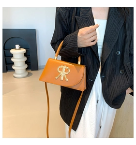 Detail of orange-brown leather small square bag with gold RR logo and top handle