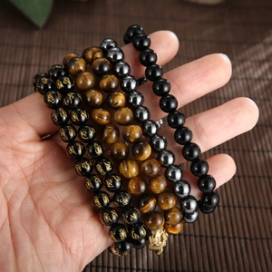 Stack of Buddhist prayer beads with obsidian tiger eye stones and a golden Buddha charm